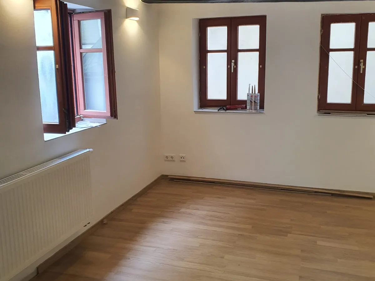 Wohnzimmer mit Holzfenstern und sichtbarem Gebälk