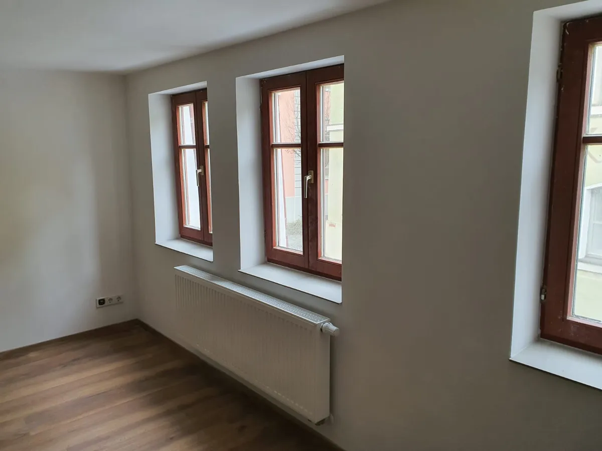 Saniertes Zimmer mit rot abgesetzten Fensterrahmen