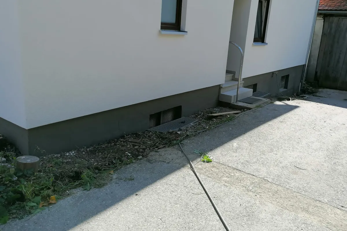 Sockelputz und frisch verputzte Fassade mit Eingang